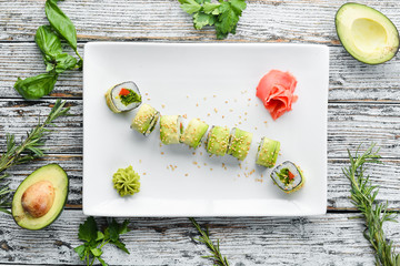 Sushi roll with avocado, cucumber and tomato. Japanese cuisine. Top view. On a white wooden background