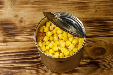 Open tin can of corn on wooden table