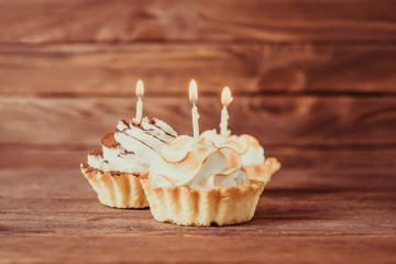 Three holiday cupcakes with burning candles.