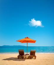 Two Lounge Chairs With Sun Umbrella On A Beach