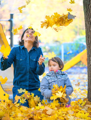 Mother and her little daugheter having fun in park with leaves