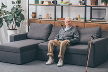 Senior Man With Grey Hair Sitting On Sofa In Living Room