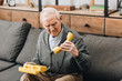 © LIGHTFIELD STUDIOS - retired man looking at old phone while sitting on sofa