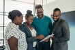 © JonoErasmus - Team of african business people standing and smiling and laughing while using a tablet