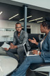 © JonoErasmus - Two african business people talking seriously with hand gestures during a meeting using their laptop and tablet
