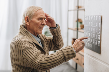 old man looking at calendar and touching head