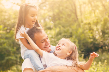 Father with his two daughters. Single father playing with his daughter outdoor on the grass.