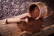 Mortar with ground coffee and pestle lie on a wooden board. Coffee pours from the mortar. Clay mugs stand on coffee beans