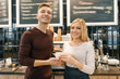 © Valerii Honcharuk - Happy smiling couple at the coffee shop counter, workers or owners with a cup of fresh art coffee looking at the camera. Small business, service, cafe