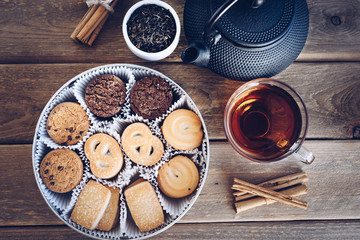 Poster - flat lay of Danish butter cookies with a cup of tea and kettle, iron, dry leaves and cinnamon