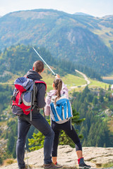 Wall Mural - Couple of hikers showing the way with trekking poles up on the mountain peak