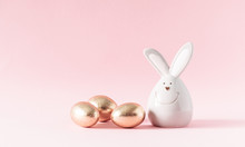 Easter Golden Eggs And Porcelain Rabbit On Pastel Pink Background. Easter, Spring Concept. Copy Space, Banner