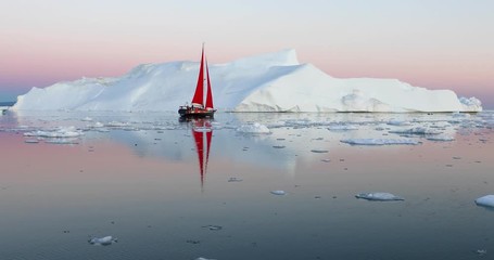 Wall Mural - little red sailboat cruising among floating icebergs in disko bay glacier during midnight sun season