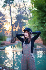 Young woman with stylish clothes posing in the green park at sunset