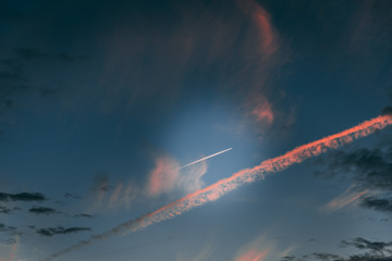 Wall Mural - Dramatic sky with pink stripes. Airplane flying in the sky