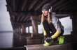 © VlaDee - sporty woman in headphones under the bridge. Young woman resting after running in winter