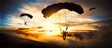 Fototapeta Na sufit - Silhouette parachutist landing at sunset