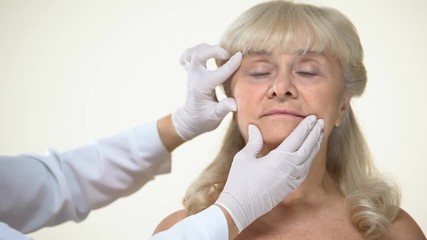 Wall Mural - Dermatologist examining elderly female patient skin, wrinkles removal, beauty