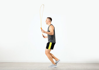 Sticker - Young sportive man training with jump rope in light room