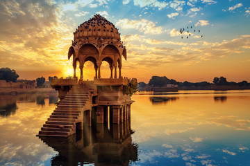 ancient architecture ruins at gadi sagar (gadisar) lake jaipur rajasthan at sunrise with vibrant moo
