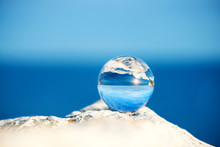  Upside Down Seascape With Blue Sky And Overgrown With Moss Rocks - Reflection In A Lensball - Selective Focus, Space For Text