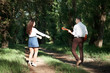 © soleg - young couple walking in the forest, playing guitar and dancing, summer nature, bright sunlight, shadows and green leaves, romantic feelings