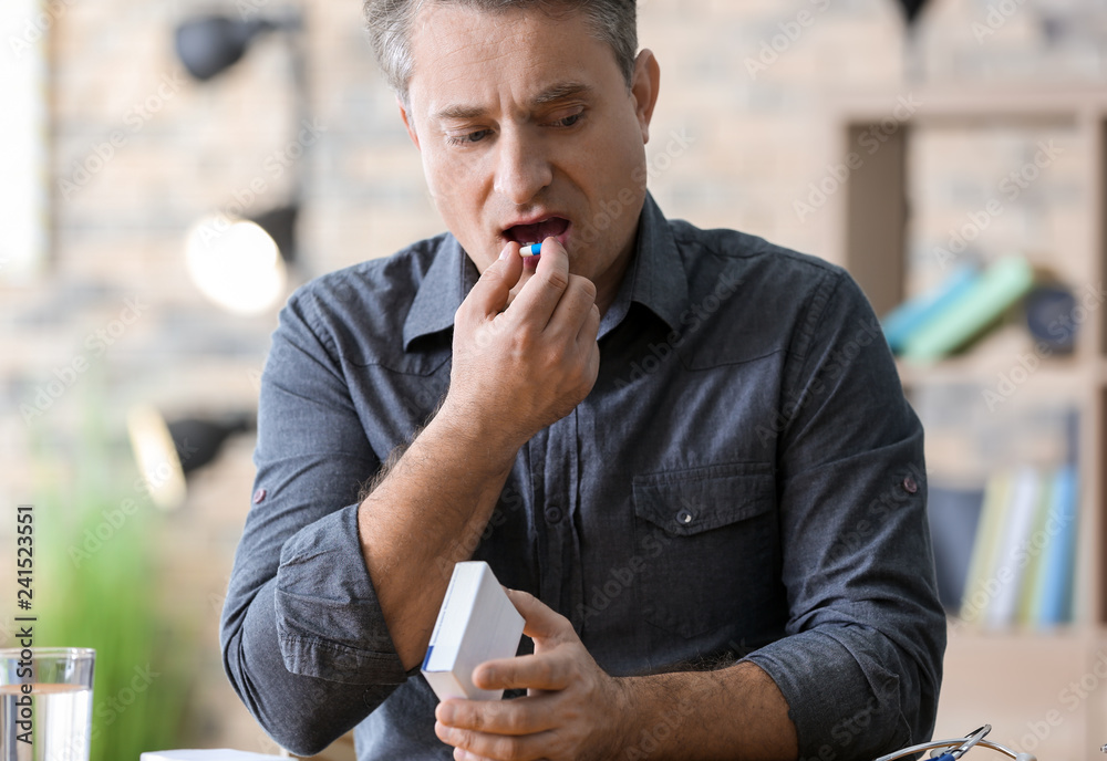 Mature man taking pill, indoors
