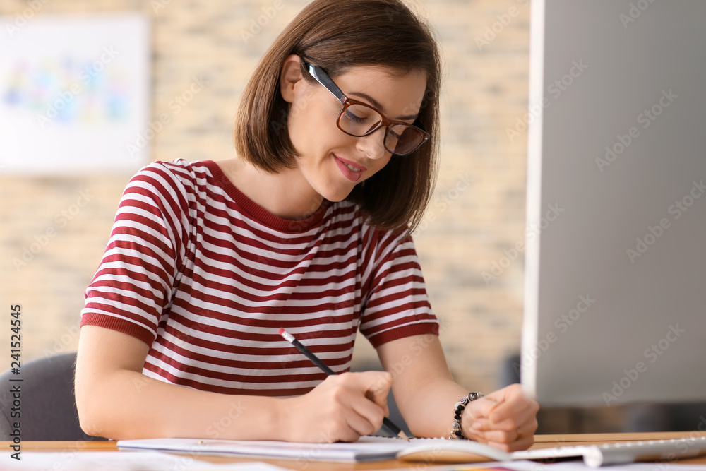 Beautiful young designer working in office
