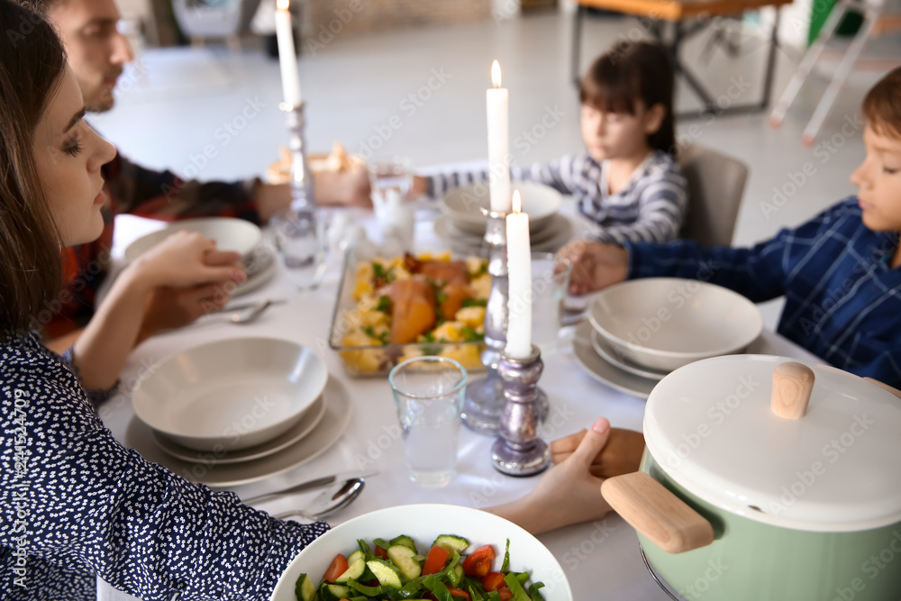 Family praying before meal at home