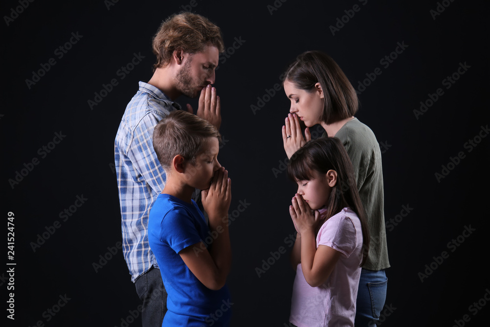 Praying family on dark background