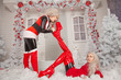 two bad Santa's girlfriends in latex costumes play in the front yard of their house at Christmas