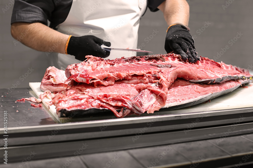 Man cleaning big tuna on table