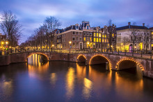 View On Romantic Canal Leidsegracht In Amsterdam At Night With City Lights, Bridges And Reflection On Water