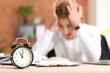 © Pixel-Shot - Alarm clock on table of stressed businessman missing deadlines
