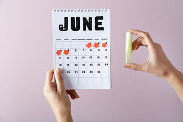 Wall Mural - Woman with menstrual calendar and tampon on color background