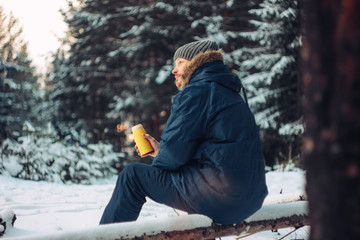 Man traveler forester hunter in the winter forest sitting on fal