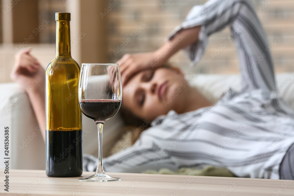 Glass and bottle of wine on table of drunk woman - obrazy, fototapety, plakaty 
