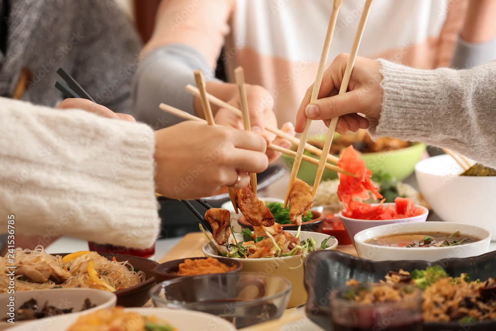Friends eating tasty Chinese food at table