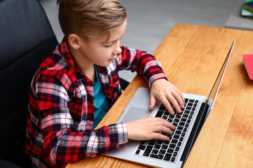 Cute boy playing video game on laptop at home