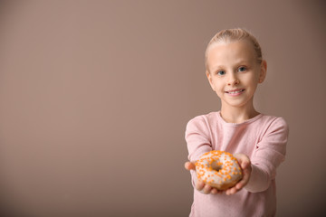 Poster - Cute little girl with donut on color background