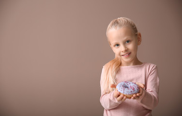 cute little girl with donut on color background