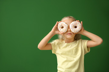 Canvas Print - Cute little girl with donuts on color background