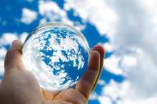 Blue Sky With Clouds Photography In Clear Crystal Glass Ball Holding In Hand.