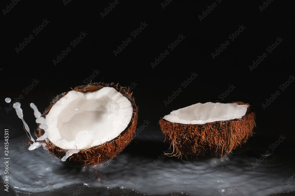 Ripe coconut and splash of milk on dark background