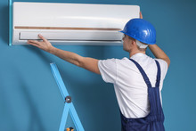 Male Technician Repairing Air Conditioner Indoors