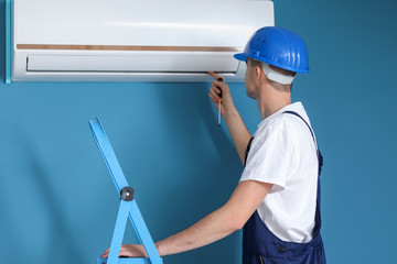 Wall Mural - Male technician repairing air conditioner indoors