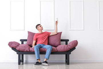 Wall Mural - Young man switching on air conditioner at home