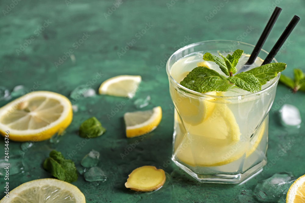 Glass of fresh lemonade on color table