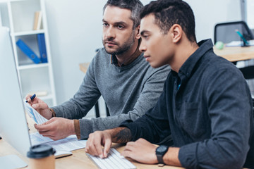 Wall Mural - focused coworkers working with papers and desktop computer in office