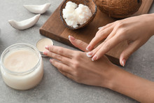 Woman Applying Coconut Oil Onto Skin On Grey Background